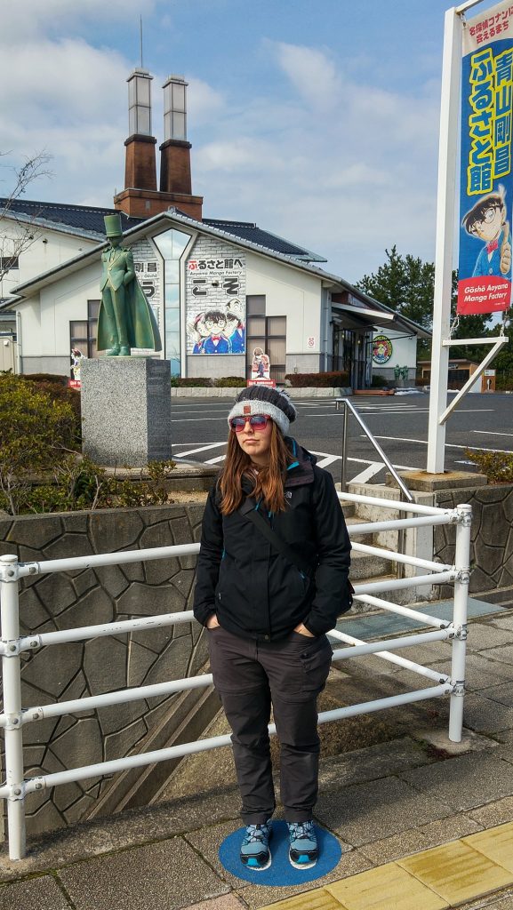 Claire pose fièrement devant la Gosho Aoyama Factory