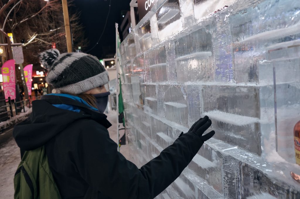 Claire touche les briques de glace d'un bar éphémère du festival de la neige de Sapporo