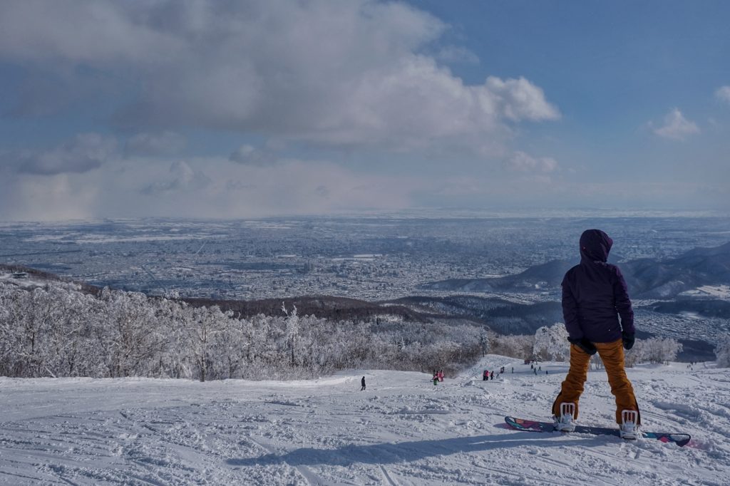 Un snowboarder contemple la ville de Sapporo