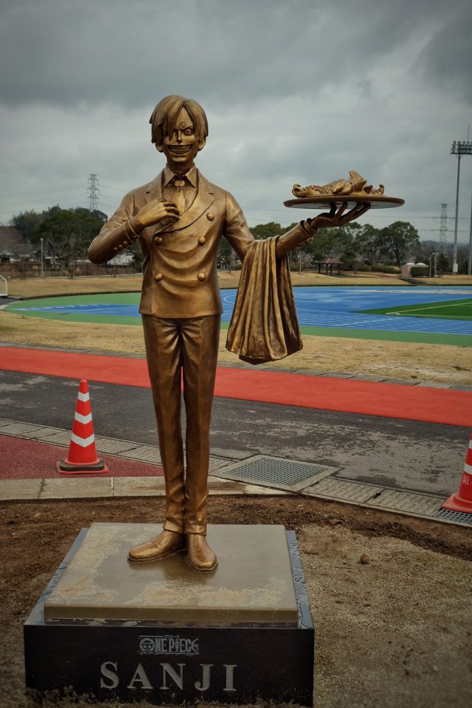 Sanji se trouve près d'un terrain de sport en périphérie de Kumamoto
