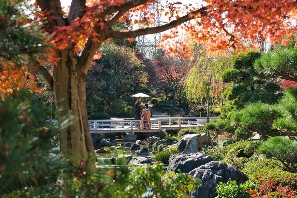 Un couple se fait prendre en photo sur un pont du jardin japonais de Daisen Sakai