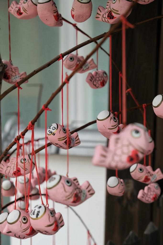 Des poissons roses à message suspendus aux arbres du sanctuaire Kitano Tenman