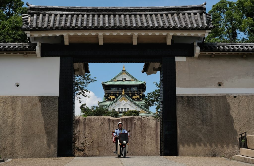 Un facteur à moto sort du château d'Osaka